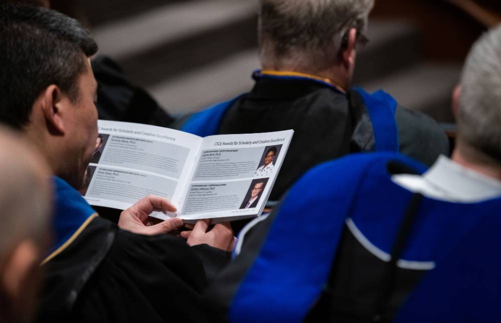 A faculty member reading the program in the audience